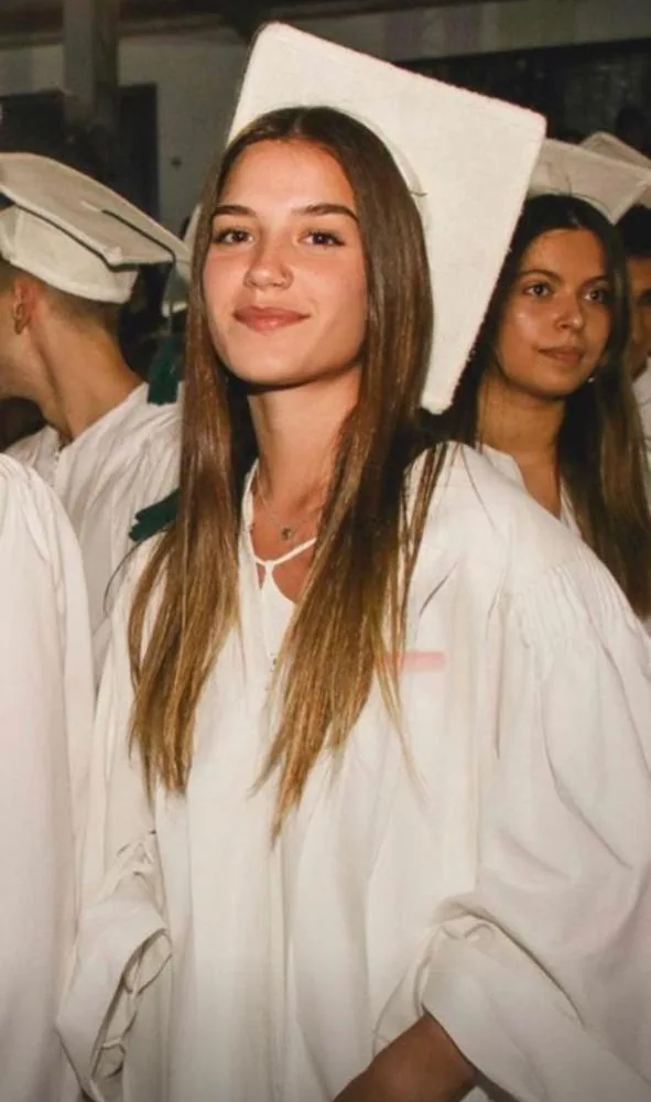Pili in a white gown at her school graduation.